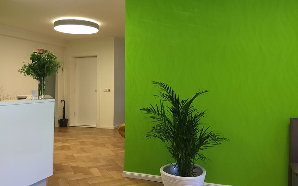 Empfangsbereich der Praxis mit neuer Rezeption und grüner Wand
